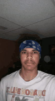 a man wearing a bandana and a dragon ball shirt looks at the camera