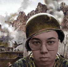 a man wearing glasses and a helmet stands in front of a painting of a tank