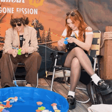 a man and a woman are fishing in front of a gone fission poster