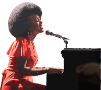 a woman singing into a microphone while playing the piano