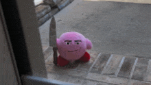 a pink kirby stuffed animal is holding a knife in its hand .