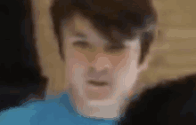 a blurry picture of a young boy in a blue shirt making a face .