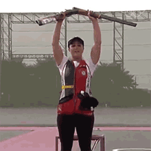 a woman is holding a shotgun over her head while wearing a vest that says ' a ' on it