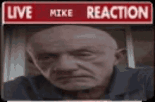 a bald man is sitting in front of a sign that says `` live mike reaction '' .