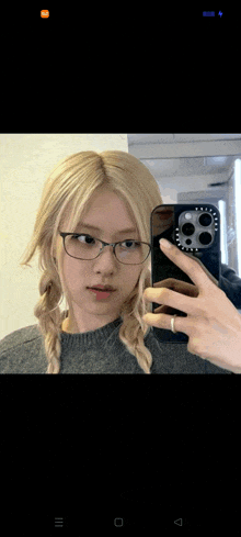 a girl wearing glasses is taking a selfie with her phone