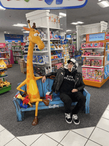 a man sits on a couch with a giraffe statue in a toy store