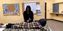 a woman is giving a person a massage in a room with a calendar on the wall that says october