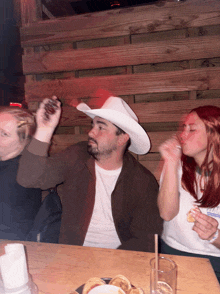 a man wearing a white cowboy hat holds a shot glass in his hand