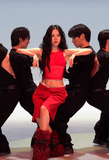 a woman in a red top and red skirt is surrounded by men in black shirts