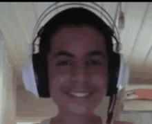 a young man wearing headphones and a microphone is smiling for the camera .