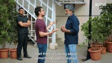 a group of men are standing next to each other in front of a building and talking about something super creative .