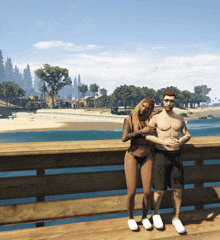 a man and a woman are posing for a picture on a pier overlooking the ocean