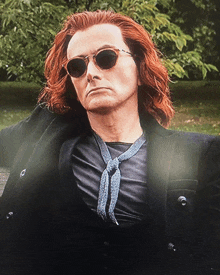 a man with red hair is wearing sunglasses and a black jacket