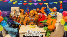 a group of toy figures are sitting around a table with balloons and a birthday cake .