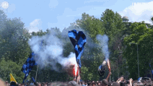 a crowd of people holding flags and flares in front of a sign that says ' i smile ' on it