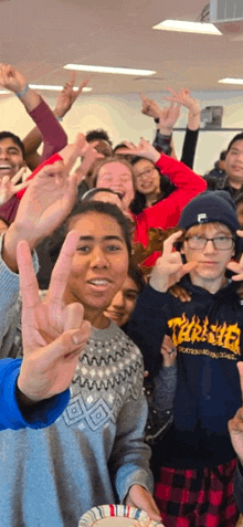 a group of young people are making peace signs with their hands .