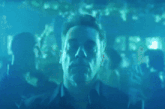 a man in a blue shirt stands in front of a crowd