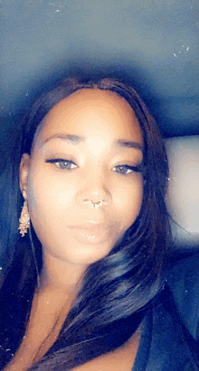 a close up of a woman 's face with a nose ring and earrings