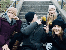 a group of people are sitting on a set of stairs and one of them is pointing at the camera