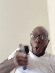 a man wearing glasses is holding a gun