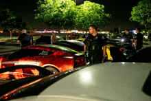 a police officer stands in front of a row of cars one of which has the letter s on the back