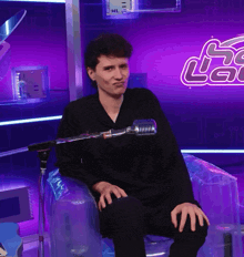 a man is sitting in a chair with a microphone in front of a sign that says lac