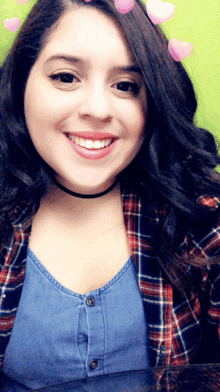 a woman wearing a plaid shirt and a choker smiles at the camera