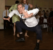 a man in a suit and tie is squatting on the floor