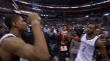 a couple of basketball players are standing next to each other in a stadium .