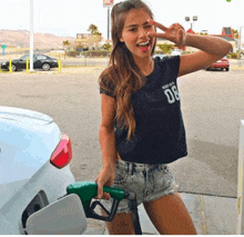 a woman in a black shirt with the number 08 on it is holding a gas pump