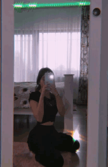 a girl is kneeling down in front of a mirror taking a picture of herself