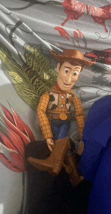 a toy story woody doll is sitting on a bed with flowers in the background