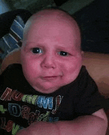 a baby is making a funny face while sitting in a crib .