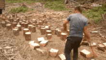 a man in a blue shirt is standing in a pile of logs with the words awesome on the bottom