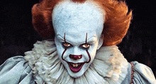 a close up of a scary clown with red hair and white makeup .