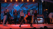 a group of people are dancing on a stage with a gorilla wearing a bgnc hat