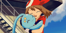 a girl in a red hat is holding a blue pokemon in her arms .