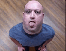 a bald man making a funny face with his tongue out