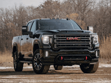 a black gmc truck is parked in the snow