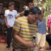 a man in a yellow and white striped shirt is holding a bottle of liquor