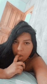 a woman with long black hair is laying on a bed taking a selfie
