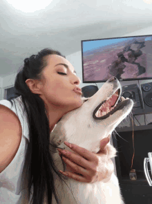 a woman kisses a dog on the nose in front of a tv