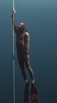 a man in a red wetsuit is holding onto a rope in the water