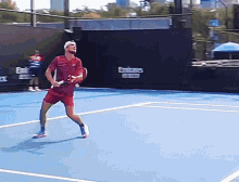 a man is holding a tennis racquet on a blue tennis court with emirates written on the wall behind him