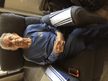 a man in a blue shirt is laying on a couch with a phone next to him