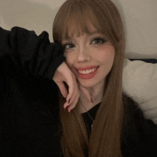 a woman with long hair and bangs is smiling while taking a selfie .