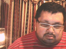 a man wearing glasses and a red shirt is looking at the camera