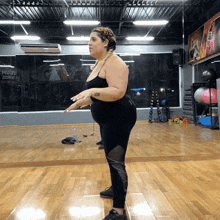 a woman stands in front of a mirror in a gym with a sign on the wall that says mugs zone