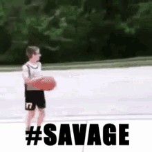 a young boy is holding a basketball on a basketball court with the words `` savage '' written above him .