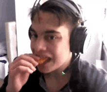 a young man wearing headphones is eating a candy bar .